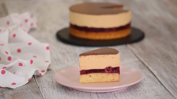 A piece of cherry cake with caramel cheese cream mousse, and chocolate glaze.	