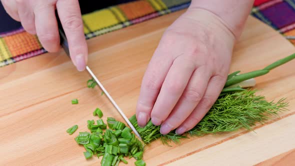 Senior Caucasian Woman Cut Green Onion and Dill on Wooden Cutting Board