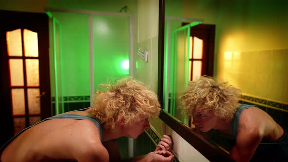 Desperate Frustrated Caucasian Queer Man Standing Up Looking at Reflection in Mirror alt