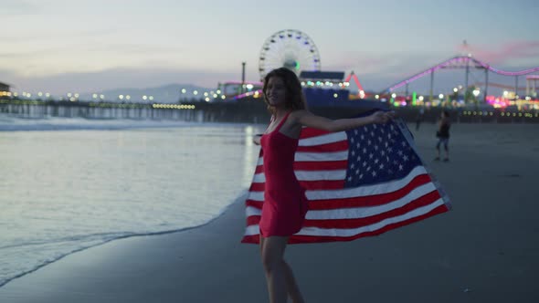 Happy girl holding the US flag, on Santa Monica beach alt