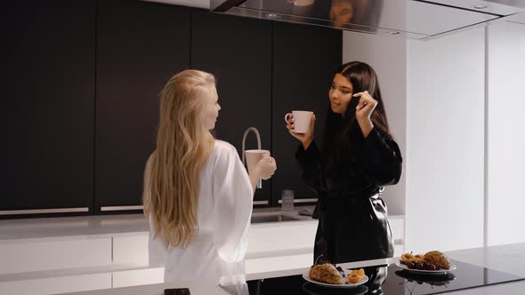 Young Darkskinned Brunette and a Young Blonde in the Kitchen in Pajamas Dancing alt