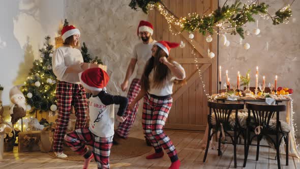 Family in Pajamas Dancing Cheerfully at Home on Christmas alt