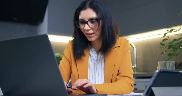 Brunette Rejoicing from Good News on Laptop Screen Sitting in Contemporary Kitchen alt