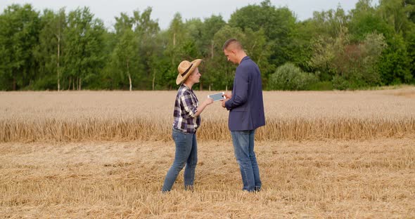 Agriculture - Female and Male Farmers Talking at Wheat Field During Harvesting alt