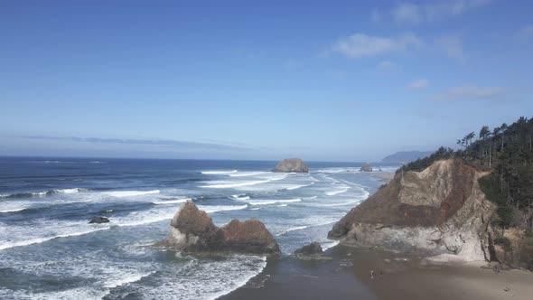 The remains of an eroded point jut out along a rugged coastline, Oregon, aerial alt