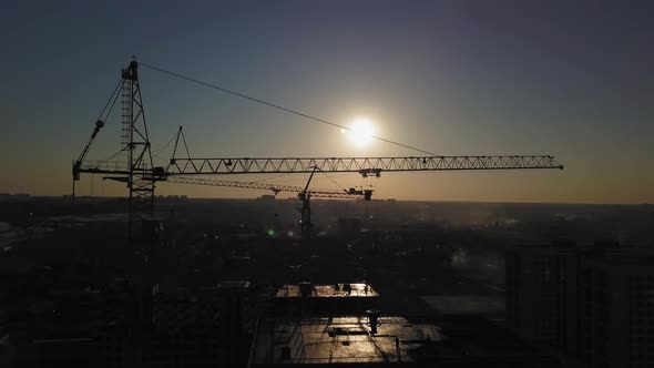 Construction Site at Sunset. Silhouette of a Construction Crane Near the Building