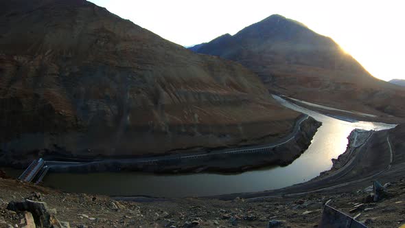 the confluence and convergence of river zanskar and indus with mountains and sun in the background alt