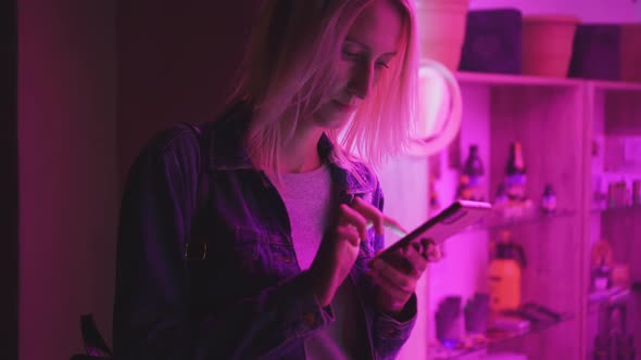 Using a mobile phone in a bright neon light. Creative bright pink color. alt