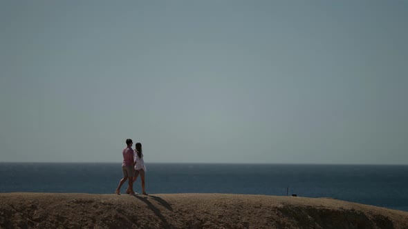 Couple is Strolling at Top of Cliff and Admiring Sea View in Summer Trip alt