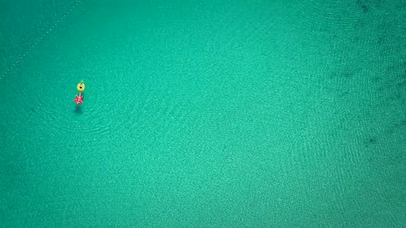 Aerial abstract view of two people floating in open sea on inflatables.