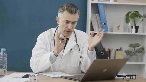 Caucasian male doctor using laptop for online meeting with patient, listens to complaints alt