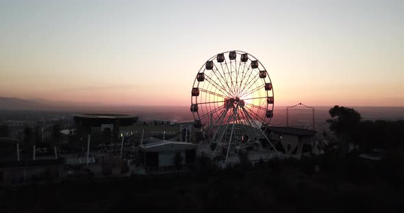 Ferris Wheel at Sunset Overlooking the City and Mountains. Almaty, Kazakhstan alt