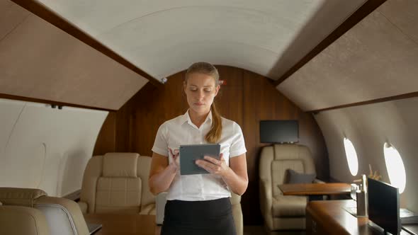 Businesswoman in Air Private Jet Surfing Internet on Tablet PC alt