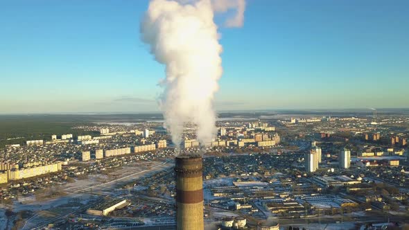 Aerial orbital shot around a heavily polluting factory chimney, as white smoke arise in a Post Sovie alt