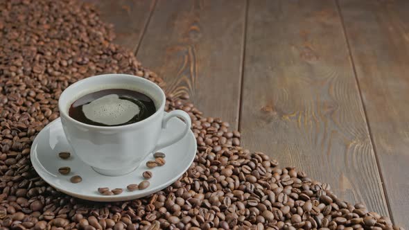 Caucasian Hand Taking and Putting Back Black Coffee in a White Cup with Spinning Bubbles on a Flat