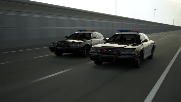 Two police cars chase. The vehicles are involved in the urgent pursuit.