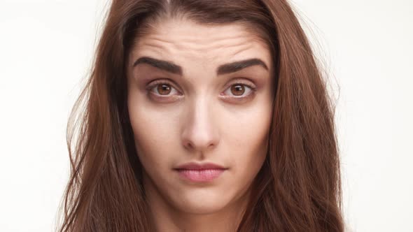 Close Up Footage of Skeptical Beautiful Caucasian Female Standing on White Background Looking alt