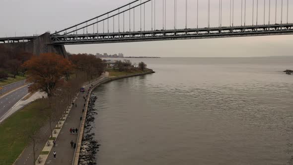 on a cloudy day the drone camera dollys in beside Shore Parkway. The Verrazzano-Narrows Bridge is in alt