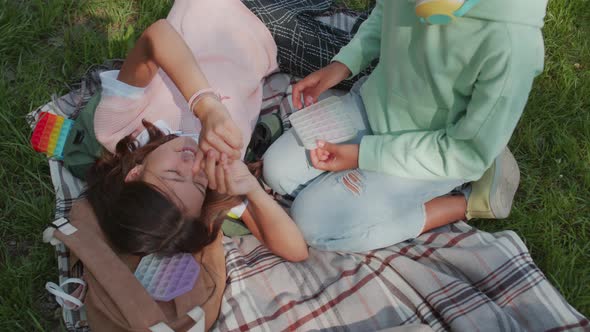 Three Children Relaxing on Blanket in Park alt