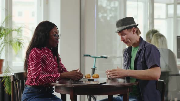 Multiethnic Young Colleagues Drink Coffee and Eat Croissants During Break alt