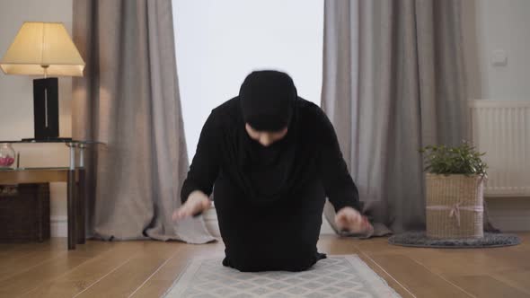 Portrait of Young Muslim Woman in Black Traditional Dress and Hijab Praying at Home, Beautiful Lady alt
