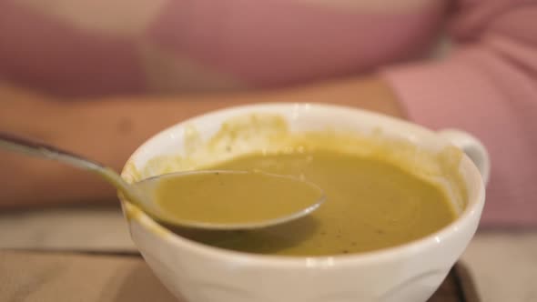 Young Woman Eating Soup in Restaurant
