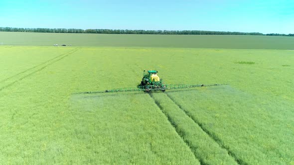 The Protection Of Plants.Tractor Spraying A Green Rapeseed Field alt