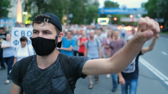 Protester Person Waves Arm Fist in Rioting Rally Crowd Under Covid Restrictions alt