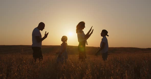 Happy Family With Children Having Fun In The Field At Sunset