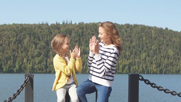 Mother and Daughter Sitting on Pier Warm Autumn Day alt