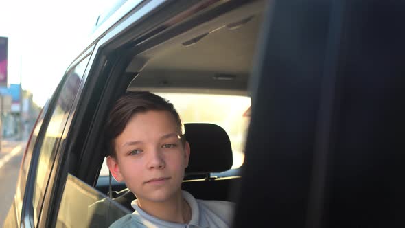 Portrait of Young Handsome Teen Traveling in a Taxi Car with a Driver in Sunny Day alt