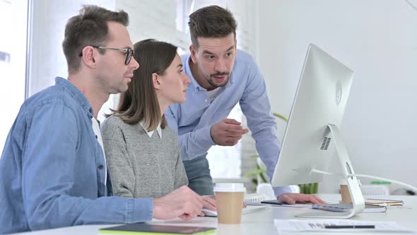 Serious Startup Team Discussing and Working on Desktop alt