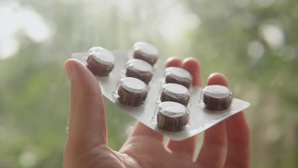 Throat Lozenges in Black Color with Chocolate Flavor in a Person's Hand
