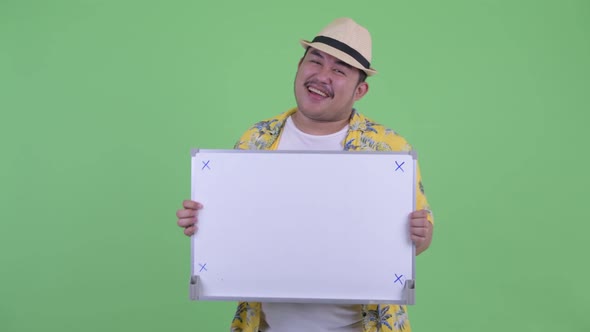 Happy Young Overweight Asian Tourist Man Dancing While Holding White Board alt