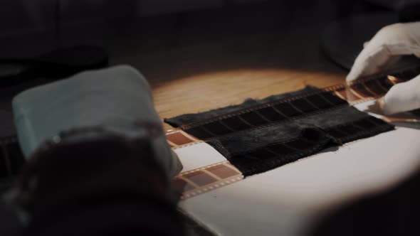A man working at a film studio examines a film strip alt