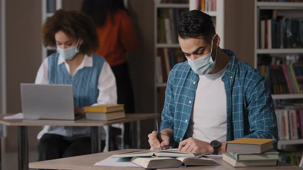 Students Study in Library Focused Intelligent Young Indian Guy in Protective Mask Sits at Desk Doing alt