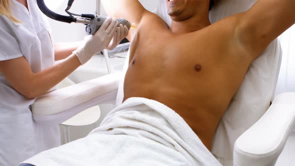 Doctor performing laser hair removal on male patient skin alt