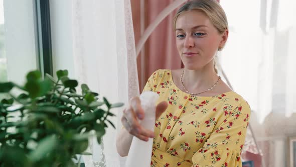 Smiling Woman Caring for Houseplant alt