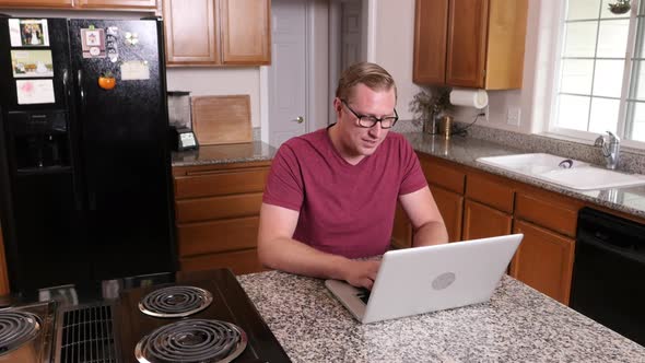 Man working on laptop computer in kitchen at home