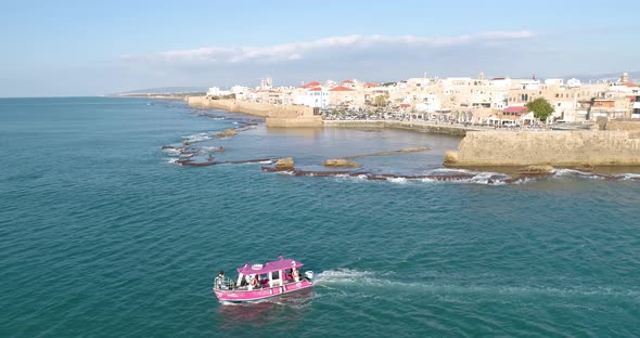 Aerial view of a passenger boat sailing near Acre old town, Israel. alt