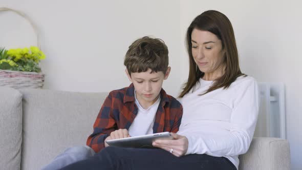 Mother watching son playing game on digital tablet