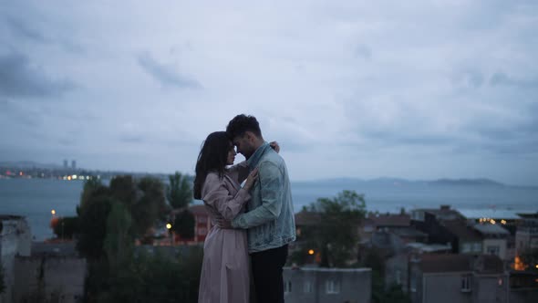 Couple Hugging Against the Backdrop of the City By the Water