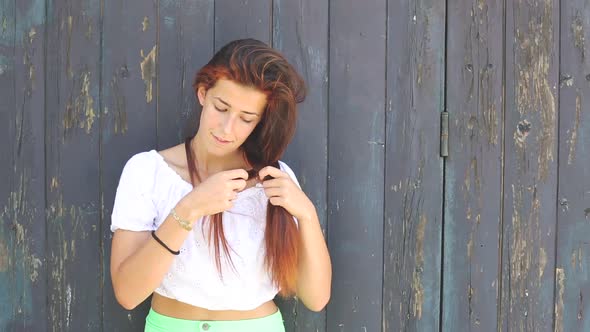 Redhead girl braiding her hair
