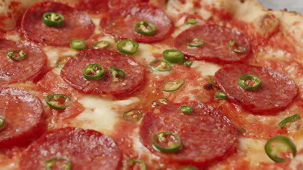 Close Up Hot Green Pepper Falls on the Pizza Ready Prepared with Pepperoni alt