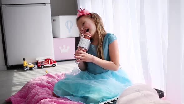 Beautiful little girl in a princess costume sings into a karaoke microphone.  Stay at home