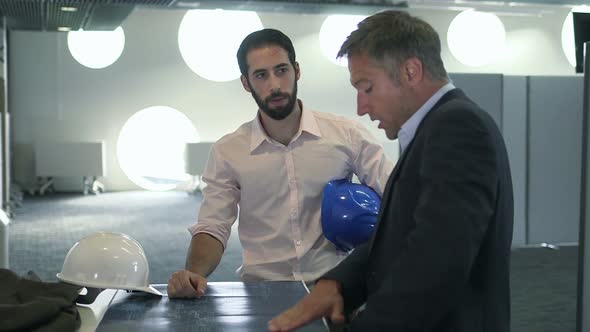 Male architect discussing with blueprint at construction site