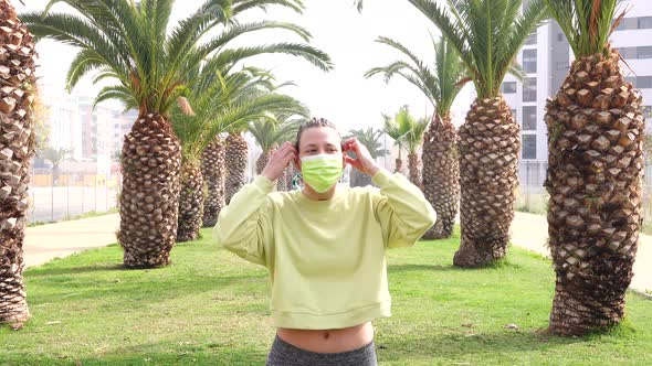 woman puts on the mask on an avenue with palm trees and grass and begins to race alt