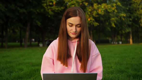 Beautiful Young Girl Student Works on a Laptop in a Park Near the University alt