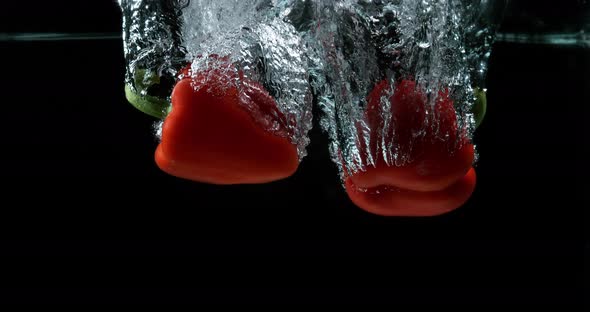 Red Sweet Pepper, capsicum annuum, Vegetable falling into Water against Black Background alt