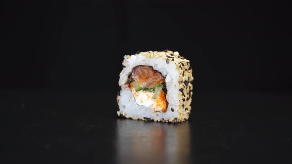 Sushi Roll Rotate on Black Background. Close-up Shoot. Philadelphia Cheese and Salmon in Japanese